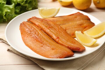 Delicious smoked herring fillets with lemon slices on white wooden table, closeup