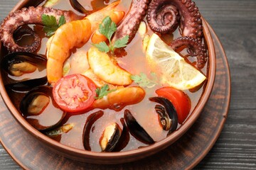 Tasty seafood soup in bowl on wooden table, closeup