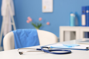 Doctor's workplace. Stethoscope, clipboard and pen on white table in medical office, closeup