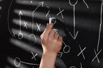 Man drawing American football game scheme on chalkboard, closeup