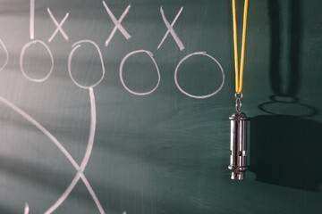 Chalkboard with scheme of American football game and whistle, closeup