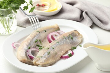 Tasty herring fillets with onions and parsley served on white table, closeup