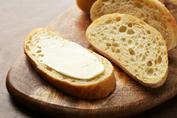 Piece of bread with butter on wooden table, closeup