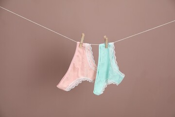 Women's underwear. Beautiful panties on clothes line against light brown background