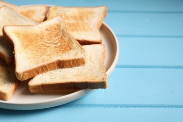 Slices of tasty toasted bread on light blue wooden table, closeup. Space for text