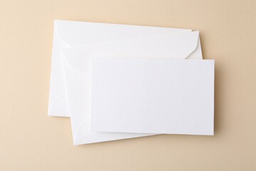 Blank greeting card and envelopes on beige background, top view
