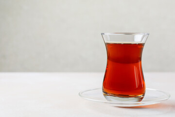 Traditional Turkish tea in glass cup on white table, closeup. Space for text