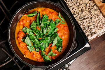 Top view of fresh tomato basil sauce in a skillet on a kitchen stove