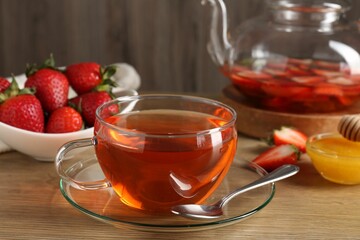 Aromatic fruit tea with strawberries and honey on wooden table, closeup