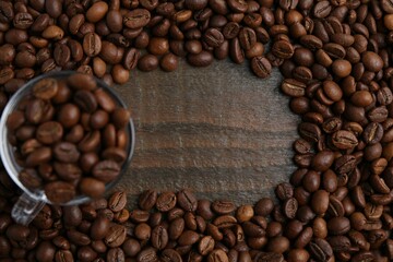Aromatic coffee beans and glass cup on wooden table, flat lay. Space for text