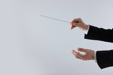 Professional conductor with baton on light grey background, closeup. Space for text