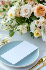 A blank card mockup on a plate on a table decorated with flowers and linen tablecloth.