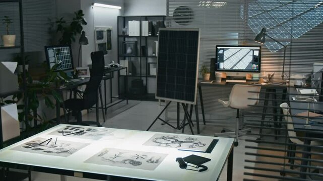 No people shot of interior of modern renewable energy office with solar panel prototype, drafting table with sketches, and workstations - tech-savvy space focused on renewable energy and innovation