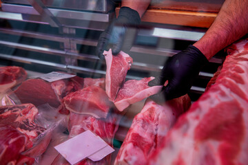 Butcher showing fresh cuts of meat in butcher shop display case