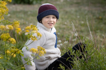 boy enjoys weather in a garden beside yellow flowers