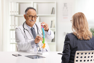 Obraz premium Mature male doctor showing a cervical spine model to a female patient