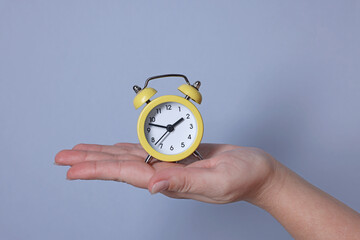 Woman with alarm clock on grey background, closeup