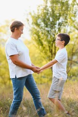 A beautiful grandmother spends time with her grandson in nature at sunset