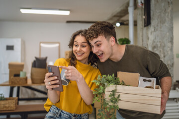 adult couple move to a new house use cellphone around cardboard boxes