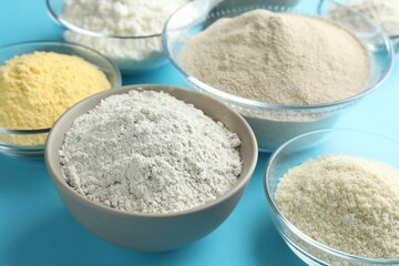 Different types of flour on light blue background, closeup
