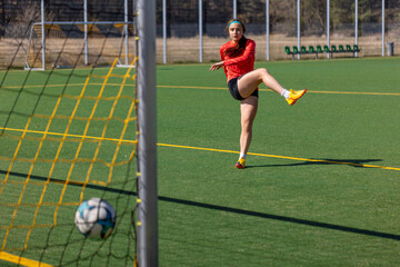 Sporty girl scores a goal into the goal. Football concept. Girl on the football field.