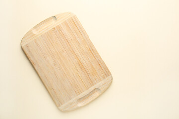 One wooden cutting board on beige table, top view. Space for text