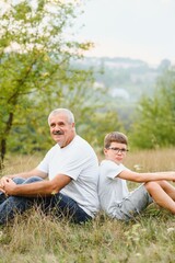 Fototapeta premium Grandfather and grandson walking at sunset