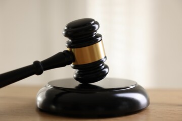 Judge's gavel on wooden table against light background, closeup