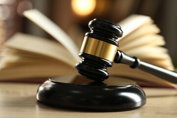 Judge's gavel and book on wooden table indoors, selective focus