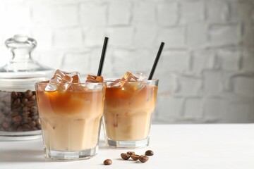 Tasty iced coffee and beans on white table. Space for text