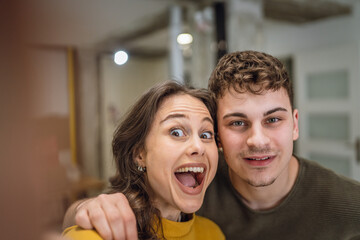 Happy young adult caucasian couple taking self portrait at new home