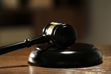 Judge's gavel and sound block on wooden table against blurred background, closeup