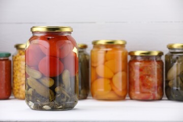 Many jars with different pickled products on white wooden table