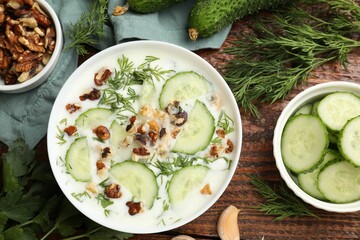 Tasty cucumber soup with dill, nuts and garlic on wooden table, flat lay
