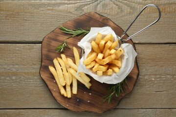 Tasty french fries with rosemary on wooden table, top view
