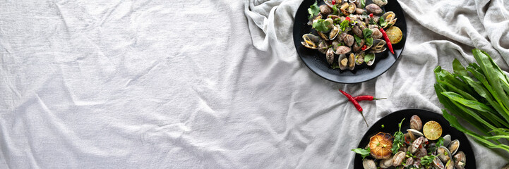 Clams and mussels are beautifully arranged with garlic, herbs, and spices on dark plates.