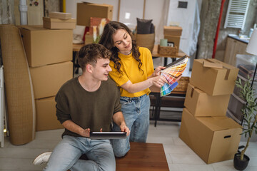 couple use tablet and color palette to choose color for paint wall