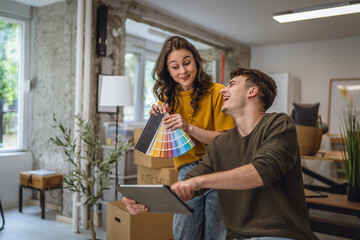 couple use tablet and color palette to choose color for paint wall
