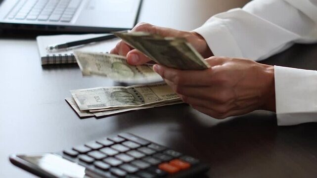 Close up view of woman's hands and Indian rupee (INR) banknotes. Concept of bank office work, saving money for retirement, cash settlement, financial success, literacy and income planning in India. 