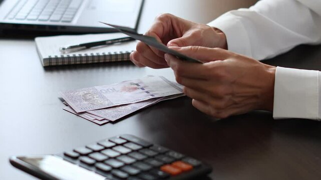 Close up view of woman's hands and Malaysian ringgit banknotes. Concept of bank office work, saving money for retirement, cash settlement, financial success, literacy and income planning in Malaysia. 