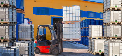 Truck for loading work on factory premises. Forklift with plastic barrels. Special warehouse equipment. Forklift moving barrels around enterprise. Unloading IBC with liquid. Forklift among barrels