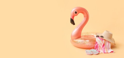 Inflatable ring and beach accessories on beige background with space for text