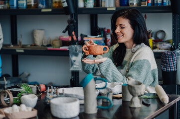 Ceramist holding a clay pot in her workshop