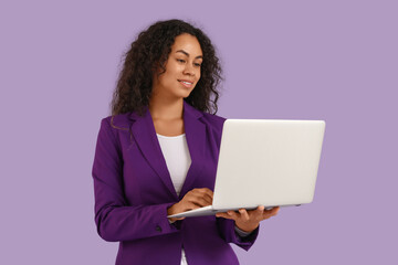 Portrait of beautiful African-American businesswoman with laptop on purple background