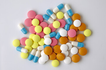 multi-colored assorted tablets and capsules scattered on white background