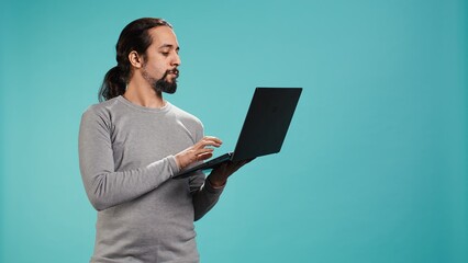 Portrait of smiling person spending time on laptop, isolated over studio background. Cheerful man...