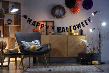 Interior of festive living room with armchair, commode and Halloween decorations in evening