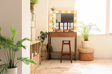 Interior of makeup room with table, glowing mirror and palm trees