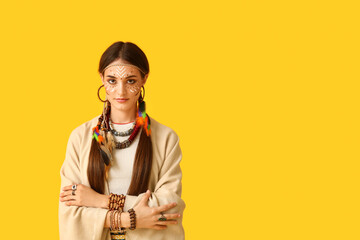 Beautiful young woman in Indian costume on yellow background. Native American Heritage Month