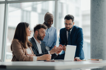 Business team discussing strategy on laptop in modern office